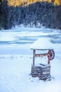 Traditional water fountain covered in snow on the side of the frozen Lacul Rosu lake