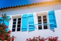 Traditional white greek white with blue window shutter in Mediterraneanstyle and rosa flowers. Fiskardo, Kefalonia Royalty Free Stock Photo