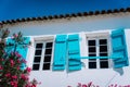 Traditional white greek white with blue window shutter in Mediterraneanstyle and rosa flowers. Fiskardo, Kefalonia Royalty Free Stock Photo