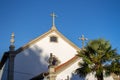 Traditional white portuguese church with palm tree in the morning. Mediterranean religious landmark. Catholic tower with cross. Royalty Free Stock Photo