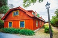 A traditional white and red painted wooden house building in Skansen open-air museum at sunny summer day.