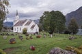 Traditional white wooden Christian church in Scandinavian style with graveyard around it. Cloudy day in Norwegian