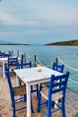 Traditional white wooden tables and chairs of a greek tavern at night and the view of the beach of Amaliapoli, Greece