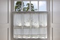 Traditional white wooden window with hand made curtain Royalty Free Stock Photo