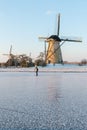 Traditional windmills and frozen canal with female skater, Kinderdijk, Netherlands Royalty Free Stock Photo