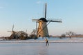 Traditional windmills and frozen canal with lonely skater, Kinderdijk, Netherlands Royalty Free Stock Photo