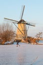 Traditional windmills and frozen canal with skater, Kinderdijk, Netherlands