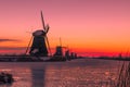 Traditional windmills on ice Kinderdijk, Netherlands at sunset, red sky Royalty Free Stock Photo