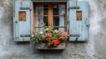 Traditional window with blue shutters and vibrant red and pink geranium flowers on a ledge Royalty Free Stock Photo