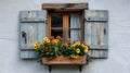 Traditional window with blue shutters and vibrant red and pink geranium flowers on a ledge Royalty Free Stock Photo