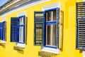 Saxon house with yellow wall and blue window blinds.