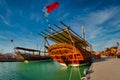 Traditional wooden boats dhows in Katara beach Qatar daylight view with Qatar flag and clouds in sky Royalty Free Stock Photo