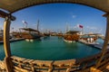 Traditional wooden boats dhows in Katara beach Qatar daylight view with Qatar flag and clouds in sky Royalty Free Stock Photo