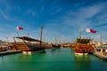 Traditional wooden boats dhows in Katara beach Qatar daylight view with Qatar flag and clouds in sky Royalty Free Stock Photo