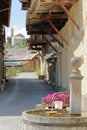 A traditional wooden fountain with traditional wooden balconies and the church in the background in Saint Veran village