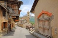 Traditional wooden houses and the church in Saint Veran village, with mountain range covered with snow in the background