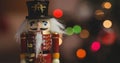 Traditional wooden nutcracker soldier figure over coloured bokeh christmas lights background Royalty Free Stock Photo