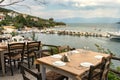 Traditional wooden tables and chairs of a greek tavern over the view of the port of Amaliapoli, Greece