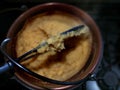 Traditional yellow corn flour Polenta from Bergamo cooked in a cauldron on fire, black background - North Italy typical food