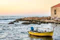 Traditional Yellow Fishing Boat and a Seaside Fish Tavern in Background in the Greek Island of Crete at Sunset. Summer in Chania Royalty Free Stock Photo