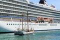 A sailing ship passes a huge cruise liner