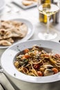 Traditioonal Italian spaghetti alle vongole e pomodorini served with flatbread and white wine