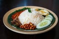 Traditonal Malaysia Asian food Nasi Lemak on a banana leaf in a wooden bamboo plate Royalty Free Stock Photo