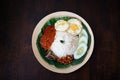 Traditonal Malaysia Asian food Nasi Lemak on a banana leaf in a wooden bamboo plate Royalty Free Stock Photo