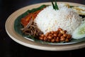 Traditonal Malaysia Asian food Nasi Lemak on a banana leaf in a wooden bamboo plate Royalty Free Stock Photo