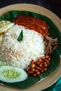 Traditonal Malaysia Asian food Nasi Lemak on a banana leaf in a wooden bamboo plate. High angle view Royalty Free Stock Photo