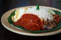 Traditonal Malaysia Asian food Nasi Lemak on a banana leaf in a wooden bamboo plate. Side view of sambal Royalty Free Stock Photo