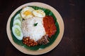 Traditonal Malaysia Asian food Nasi Lemak on a banana leaf in a wooden bamboo plate. Top view Royalty Free Stock Photo