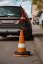 Traffic cone behind a broken down vehicle Orange traffic sign and a damaged car