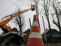 Traffic cone, close-up, on the background of bucket truck with workers. Two men with a chainsaw, standing on the aerial device on