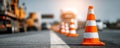 Traffic cone on road with blurred vehicles and other cones in background during sunset light Royalty Free Stock Photo