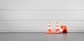 Traffic cones along wall, front view. Realistic orange warning sings on street or in room with white tile wall and grey