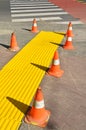 Traffic cones on the sidewalk next to a zebra crossing