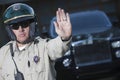 Traffic Cop Signaling Stop Gesture With Car In Background