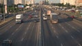 Traffic on an eight-lane asphalt road of cars, trucks, buses.