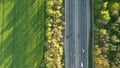 Traffic on the highway through deep forest aerial view.