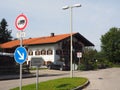 Traffic island with road signs in front of a Bavarian house