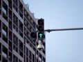 A traffic light with a freen light is on a street in front of a building. A CCTV security camera is mounted on the Royalty Free Stock Photo