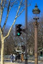 Traffic light, lantern, tree against the blue sky in spring in Paris, where people walk in good weather