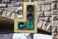 Traffic light with on left arrow section and a permissive green signal closeup on the background of arches of a stone bridge in Royalty Free Stock Photo