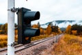 A traffic light at a level crossing with a yellow signal - autumn trees in brightly colored warm colors and gentle fog