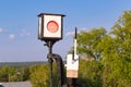 Traffic light on the railway in the village against the background of the forest and blue sky with white clouds on a bright sunny Royalty Free Stock Photo