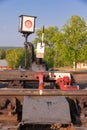 Traffic light on the railway in the village against the background of the forest and blue sky with white clouds on a bright sunny Royalty Free Stock Photo