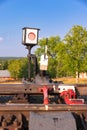 Traffic light on the railway in the village against the background of the forest and blue sky with white clouds on a bright sunny Royalty Free Stock Photo