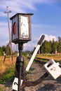 Traffic light on the railway in the village against the background of the forest and blue sky with white clouds on a bright sunny Royalty Free Stock Photo