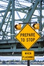 Traffic light warning signal with traffic sign prepare to stop on the access road to the truss drawbridge over the river